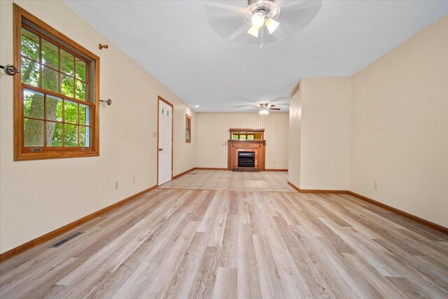 8491 Surrey Cir, Bloomington, IL 61705 - unfurnished living room with a ceiling fan, light wood-style flooring, a brick fireplace, baseboards, and a textured ceiling