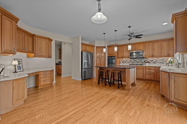 36W703 Whispering Trl, Saint Charles, IL 60175 - kitchen with appliances with stainless steel finishes, a sink, a breakfast bar area, a kitchen island, and light wood-type flooring