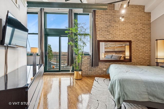 2222 W Diversey Ave Unit 407, Chicago, IL 60647 - bedroom with wood finished floors, brick wall, multiple windows, and rail lighting