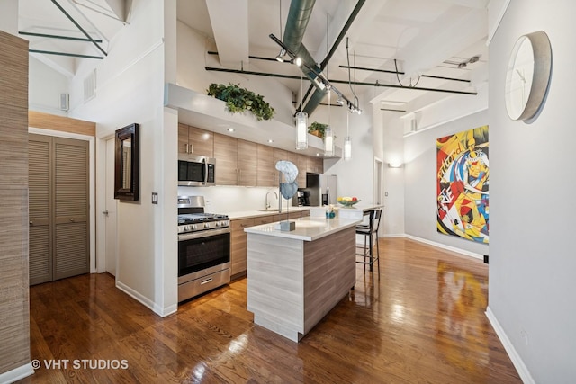2222 W Diversey Ave Unit 407, Chicago, IL 60647 - kitchen with stainless steel appliances, modern cabinets, light countertops, a breakfast bar area, and dark wood-style flooring