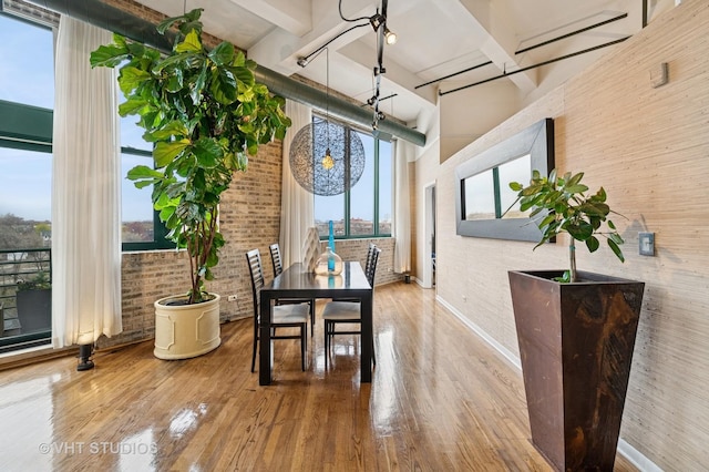 2222 W Diversey Ave Unit 407, Chicago, IL 60647 - dining area featuring brick wall, wood finished floors, a towering ceiling, and baseboards