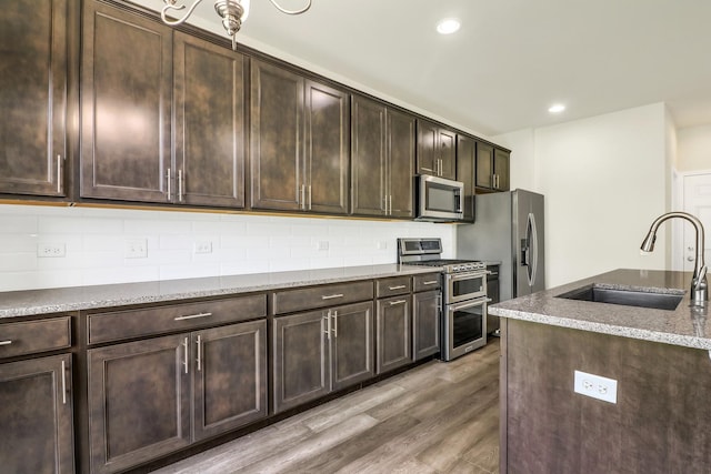 415 Highcroft Way, Lincolnshire, IL 60069 - kitchen with stainless steel appliances, a sink, light wood finished floors, light stone counters, and backsplash