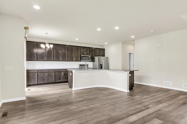 415 Highcroft Way, Lincolnshire, IL 60069 - kitchen with appliances with stainless steel finishes, a chandelier, a kitchen island with sink, dark brown cabinetry, and light wood finished floors
