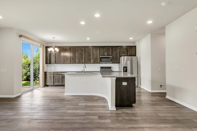 415 Highcroft Way, Lincolnshire, IL 60069 - kitchen featuring appliances with stainless steel finishes, an island with sink, dark brown cabinetry, a chandelier, and wood finished floors