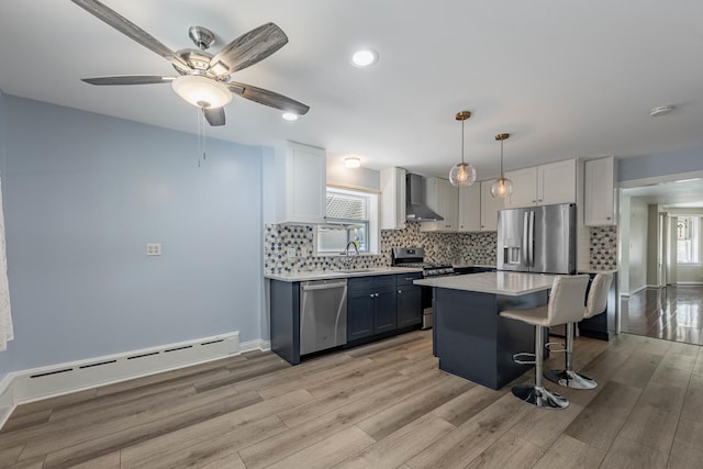 2535 Oak Park Ave, Berwyn, IL 60402 - kitchen featuring appliances with stainless steel finishes, baseboard heating, wall chimney range hood, a sink, and a kitchen breakfast bar