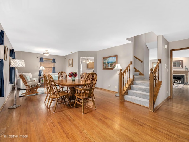 824 Dawes Ave, Wheaton, IL 60189 - dining room featuring light wood-style floors, stairs, a fireplace, and a chandelier