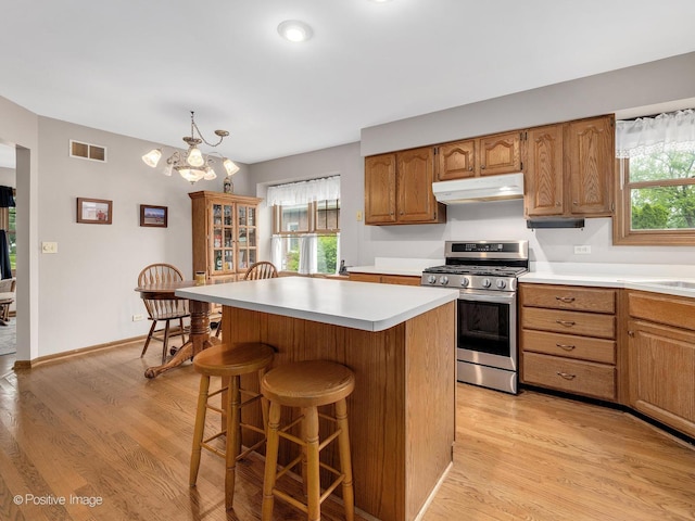 824 Dawes Ave, Wheaton, IL 60189 - kitchen with stainless steel gas range, under cabinet range hood, light countertops, a kitchen breakfast bar, and light wood-style floors