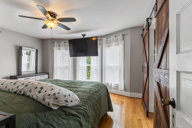 1104 W Church St, Champaign, IL 61821 - bedroom with a barn door, light wood finished floors, baseboards, and a ceiling fan