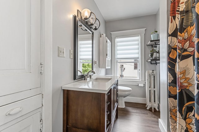 1104 W Church St, Champaign, IL 61821 - bathroom with toilet, vanity, radiator, wood finished floors, and baseboards