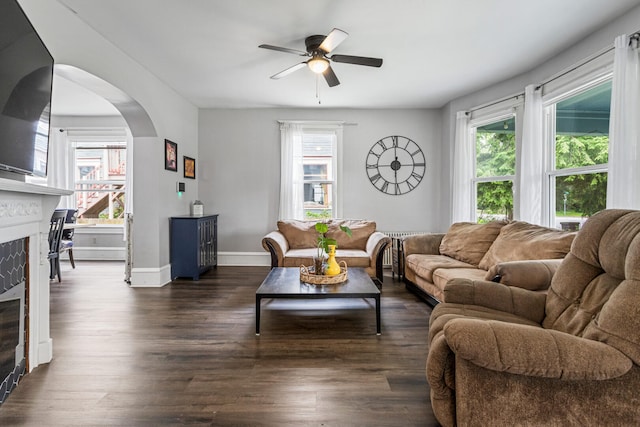1104 W Church St, Champaign, IL 61821 - living room featuring a fireplace, ceiling fan, arched walkways, dark wood-style floors, and baseboards