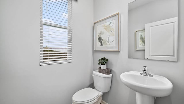 half bath with a sink, baseboards, and toilet