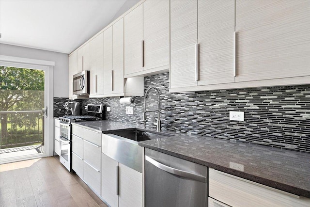 466 Elizabeth Dr Unit 17-C, Wood Dale, IL 60191 - kitchen featuring appliances with stainless steel finishes, a sink, decorative backsplash, light wood-type flooring, and dark stone counters