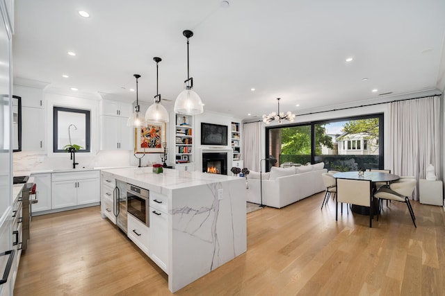 1719 N Burling St Unit 2S, Chicago, IL 60614 - kitchen featuring a center island, white cabinetry, light stone counters, pendant lighting, and recessed lighting