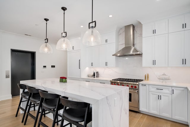 1719 N Burling St Unit 2S, Chicago, IL 60614 - kitchen with luxury stove, wall chimney range hood, a kitchen island, light stone countertops, and light wood-style flooring