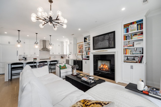1719 N Burling St Unit 2S, Chicago, IL 60614 - living room featuring a chandelier, light wood-style floors, a warm lit fireplace, recessed lighting, and ornamental molding