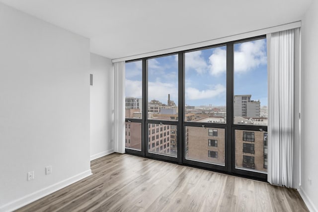 210 S Desplaines St Unit 1102, Chicago, IL 60661 - unfurnished room featuring a city view, a wall of windows, baseboards, and wood finished floors