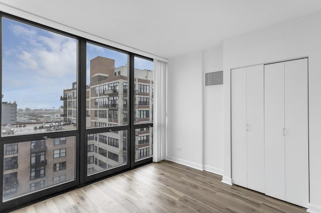 210 S Desplaines St Unit 1102, Chicago, IL 60661 - unfurnished bedroom with wood finished floors, a city view, baseboards, and a wall of windows
