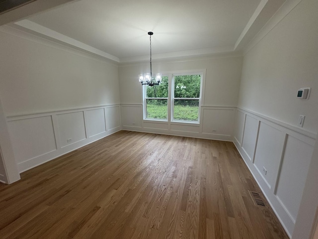 154 Pine Ln, Wood Dale, IL 60191 - unfurnished dining area with a chandelier, wainscoting, wood finished floors, a decorative wall, and a tray ceiling