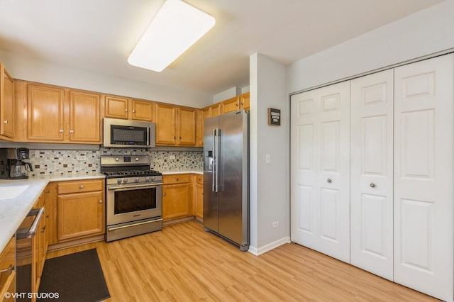 1040 Fairway Dr, Fox Lake, IL 60020 - kitchen with appliances with stainless steel finishes, light wood-style floors, light countertops, decorative backsplash, and brown cabinets