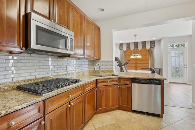 kitchen featuring appliances with stainless steel finishes, a sink, tasteful backsplash, a chandelier, and a peninsula