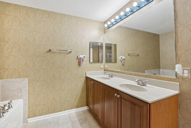 bathroom with a garden tub, double vanity, and baseboards