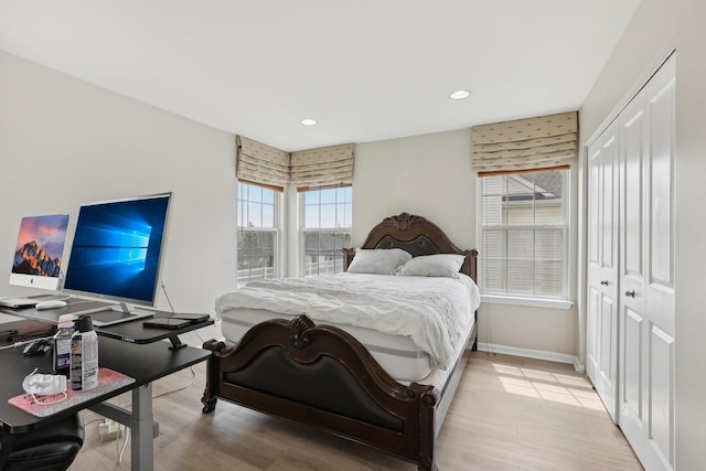 bedroom with a closet, baseboards, recessed lighting, and light wood-style floors