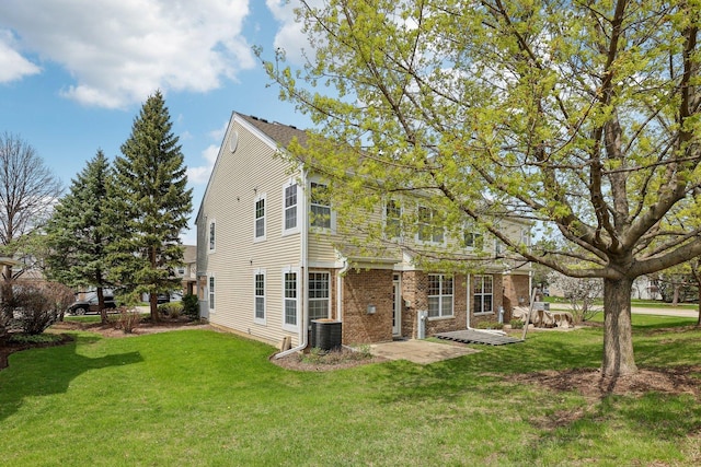 back of property with a lawn, a patio, central AC unit, and brick siding