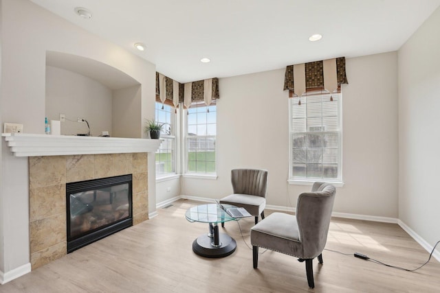 sitting room with wood finished floors, baseboards, a tile fireplace, and recessed lighting