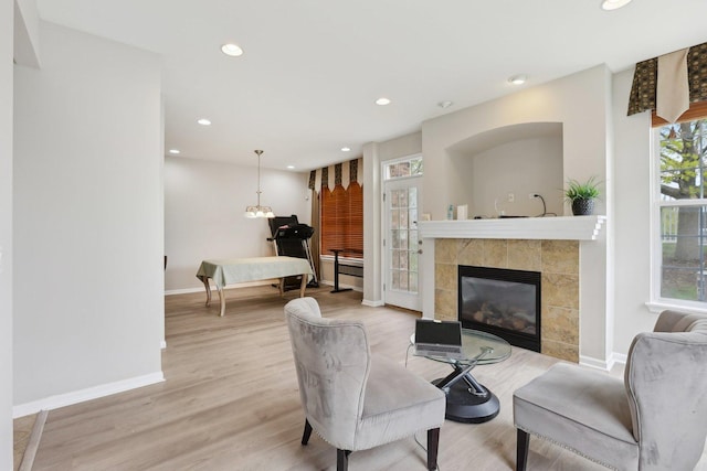 living area with baseboards, light wood finished floors, recessed lighting, and a tile fireplace