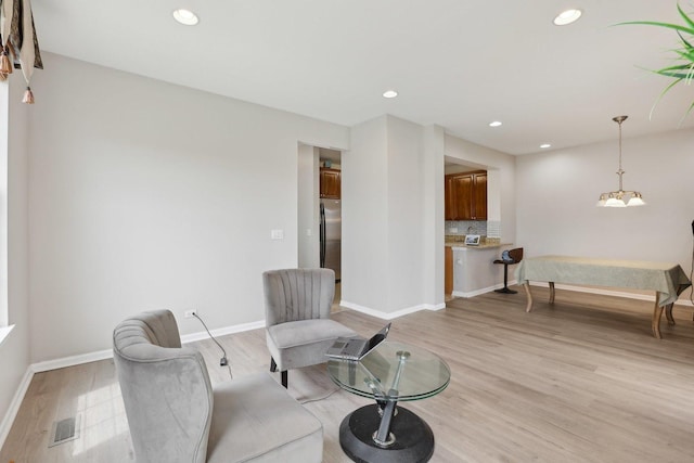 living area with light wood-style flooring, recessed lighting, baseboards, and a chandelier