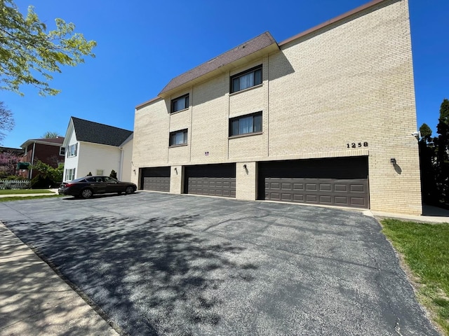 1258 Brown St Unit 302, Des Plaines, IL 60016 - view of home's exterior featuring brick siding, a garage, and driveway