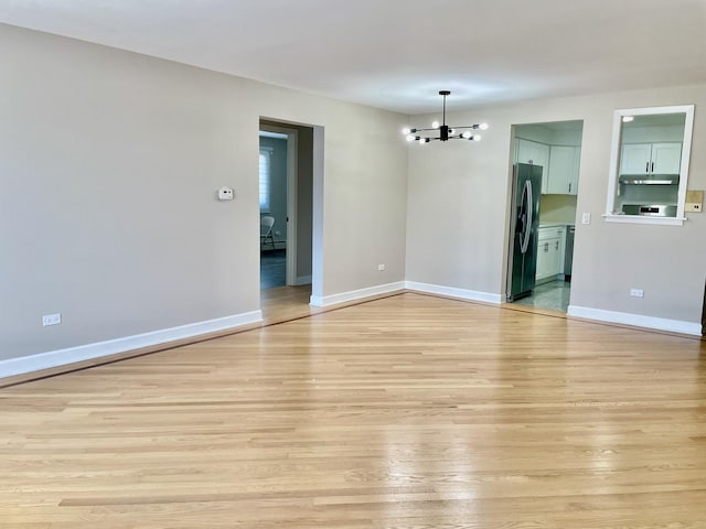 1258 Brown St Unit 302, Des Plaines, IL 60016 - spare room featuring a chandelier, light wood-style floors, and baseboards