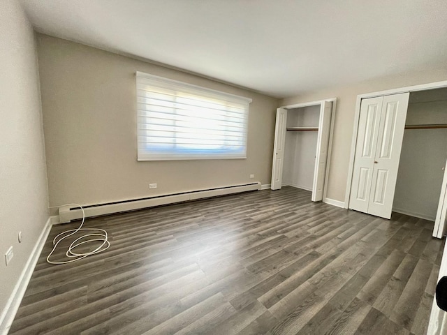 1258 Brown St Unit 302, Des Plaines, IL 60016 - unfurnished bedroom featuring baseboard heating, two closets, dark wood-type flooring, and baseboards