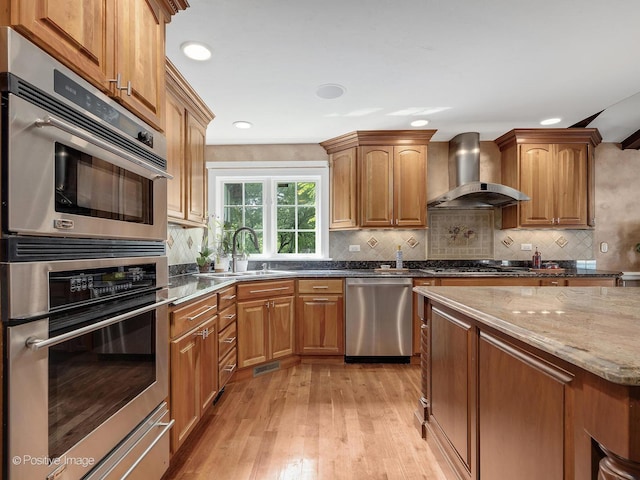 6 Swaps Ct, Oak Brook, IL 60523 - kitchen featuring stainless steel appliances, wall chimney range hood, light wood-style flooring, stone counters, and tasteful backsplash