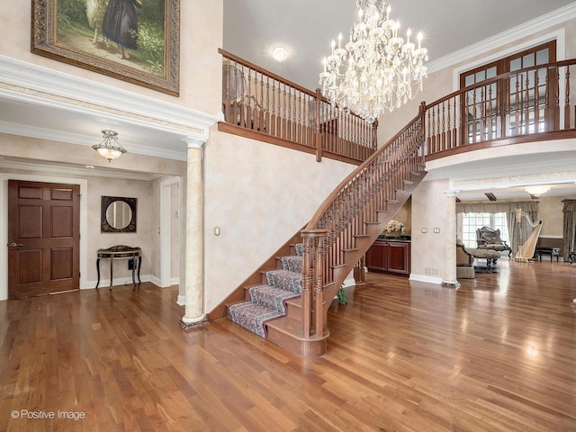 6 Swaps Ct, Oak Brook, IL 60523 - staircase featuring a towering ceiling, wood finished floors, crown molding, ornate columns, and a chandelier