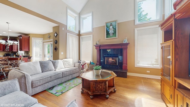 17040 Cheyenne Ct, Lockport, IL 60441 - living room featuring light wood-style floors, high vaulted ceiling, a tiled fireplace, a chandelier, and baseboards