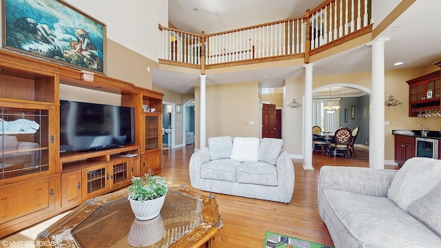 17040 Cheyenne Ct, Lockport, IL 60441 - living area featuring decorative columns, wood finished floors, arched walkways, beverage cooler, and a high ceiling