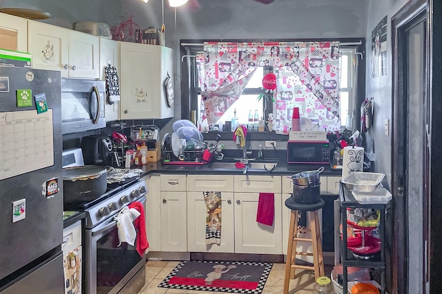 10817 S Forest Ave, Chicago, IL 60628 - kitchen featuring appliances with stainless steel finishes, dark countertops, light tile patterned flooring, white cabinetry, and a sink