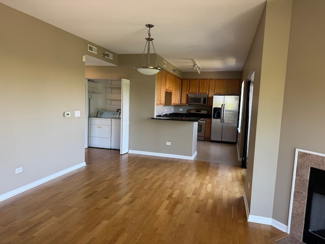 100 N Hermitage Ave Unit 409, Chicago, IL 60612 - kitchen featuring stainless steel appliances, wood finished floors, separate washer and dryer, dark countertops, and open floor plan