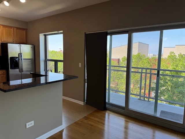 100 N Hermitage Ave Unit 409, Chicago, IL 60612 - kitchen featuring stainless steel refrigerator with ice dispenser, wood finished floors, baseboards, brown cabinets, and dark stone countertops