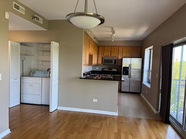 100 N Hermitage Ave Unit 409, Chicago, IL 60612 - kitchen with appliances with stainless steel finishes, independent washer and dryer, wood finished floors, brown cabinetry, and plenty of natural light