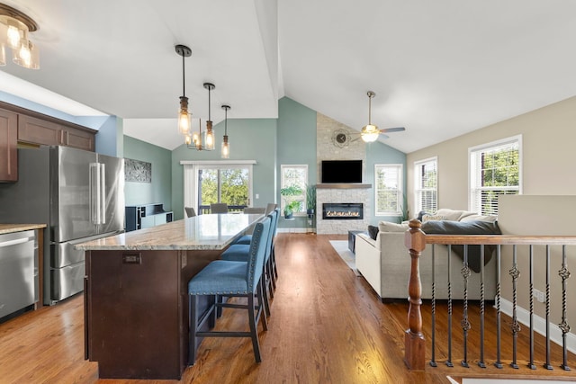 24608 George Washington Dr, Plainfield, IL 60544 - kitchen with stainless steel appliances, a ceiling fan, wood finished floors, a kitchen island, and high vaulted ceiling