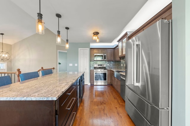 24608 George Washington Dr, Plainfield, IL 60544 - kitchen featuring appliances with stainless steel finishes, tasteful backsplash, decorative light fixtures, dark wood-style flooring, and a center island