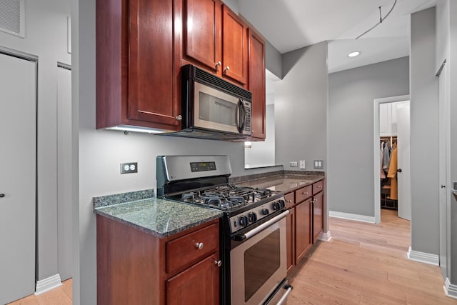 550 W Fulton St Unit 303, Chicago, IL 60661 - kitchen with stainless steel appliances, light wood finished floors, baseboards, dark stone counters, and recessed lighting