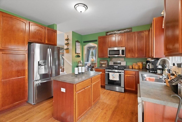 605 Acorn Ct, Antioch, IL 60002 - kitchen with appliances with stainless steel finishes, a sink, a center island, arched walkways, and light wood-style flooring