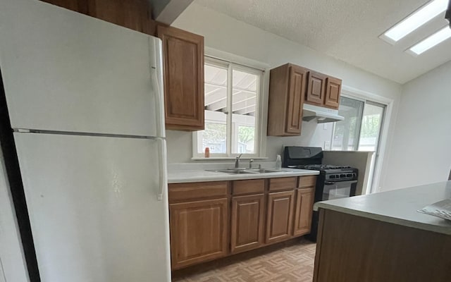 807 Finch Trl, Mchenry, IL 60051 - kitchen featuring freestanding refrigerator, a sink, under cabinet range hood, black range with gas stovetop, and light countertops