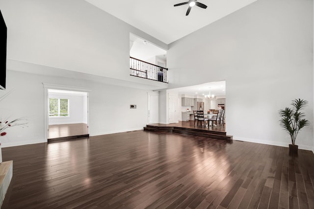 24161 Brancaster Dr, Naperville, IL 60564 - unfurnished living room featuring a towering ceiling, ceiling fan, dark wood-type flooring, a chandelier, and baseboards