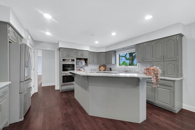 24161 Brancaster Dr, Naperville, IL 60564 - kitchen with gray cabinetry, stainless steel appliances, dark wood finished floors, baseboards, and a breakfast bar