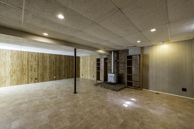 10100 W Chaplin Ave, Beach Park, IL 60087 - finished below grade area featuring a wood stove, wooden walls, a paneled ceiling, recessed lighting, and tile patterned floors