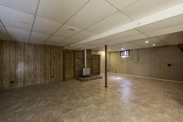 10100 W Chaplin Ave, Beach Park, IL 60087 - finished basement featuring a wood stove, a paneled ceiling, wooden walls, tile patterned floors, and recessed lighting